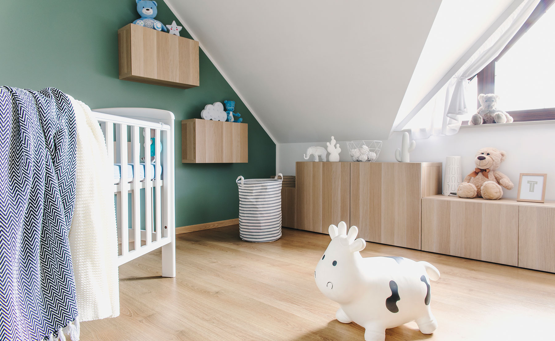 Skandinavisk indrettet børneværelse med en seng og legetøj på gulvet.